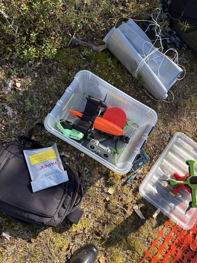Field kit laid out on the ground: a storage box with shell parts, a battery safety bag and tools